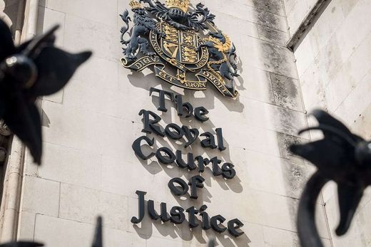 The Royal Courts of Justice sign and royal coat of arms carved above the entrance in London.