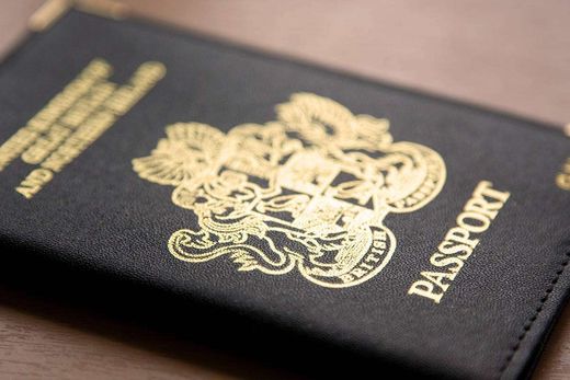 Close-up of the gold royal coat of arms embossed on the cover of a British passport.