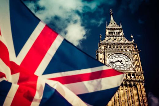 A Union flag flying in front of the Elizabeth Tower and Big Ben clock face in Westminster.