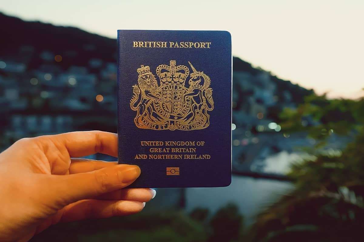 A newly issued first British passport lying on top of the completed application forms - the first-passport route is the moment naturalisation becomes practical.