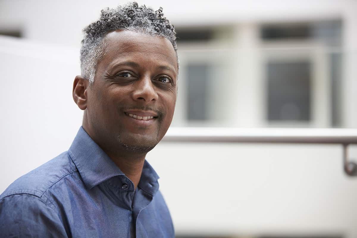 An older Commonwealth-born UK resident holding immigration papers from the 1960s - Windrush Scheme applications are free and confirm a right to stay that has often been held for decades.