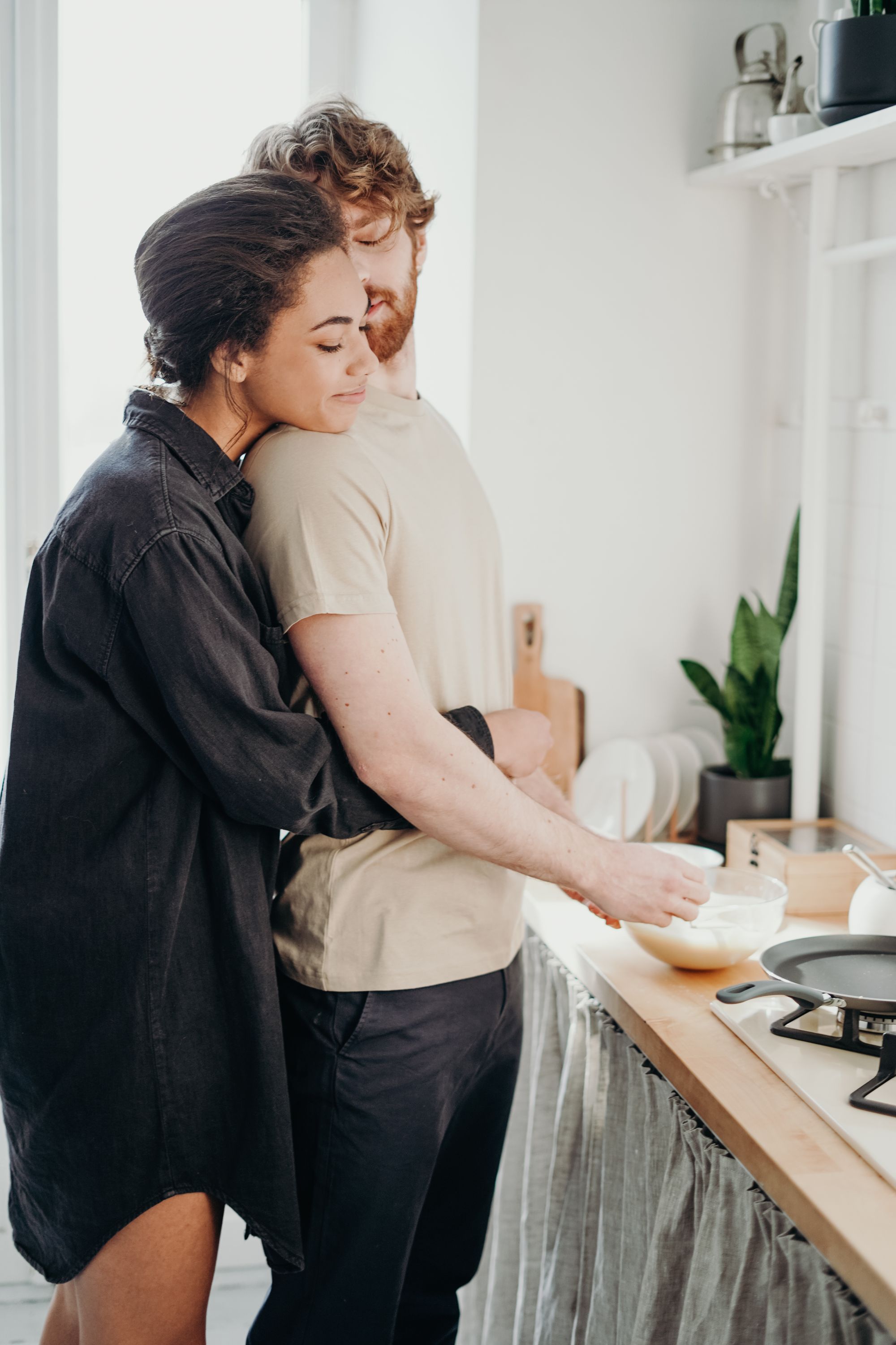 A young couple embracing at a kitchen counter - once the ceremony is done and you switch to the spouse visa, this is the everyday life the route was for.