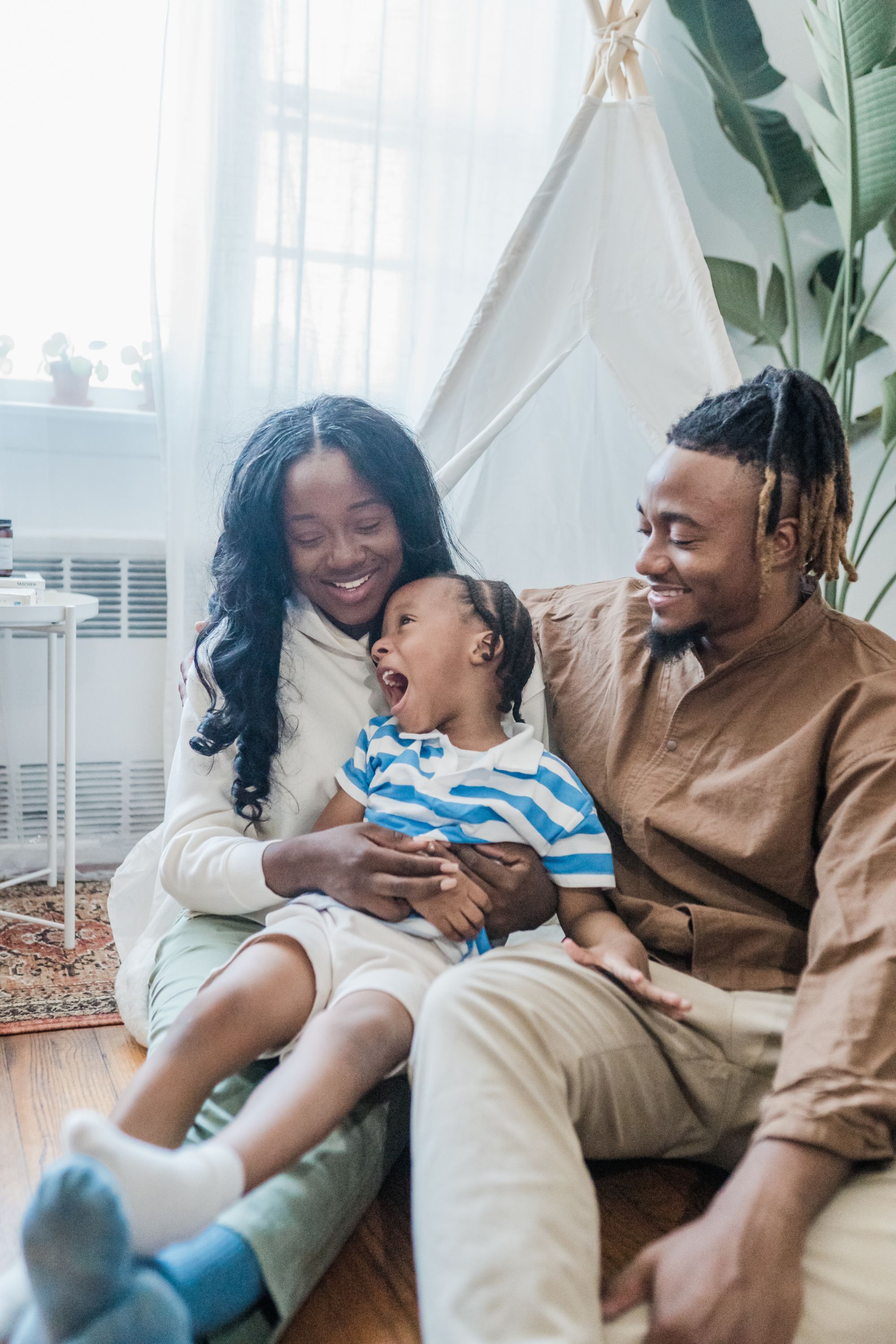 A young child laughing on their parents' laps at home - the ongoing shared moments of daily life are exactly the evidence the parent-route decision turns on.